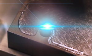 two pieces of metal being laser welded together by a blue laser